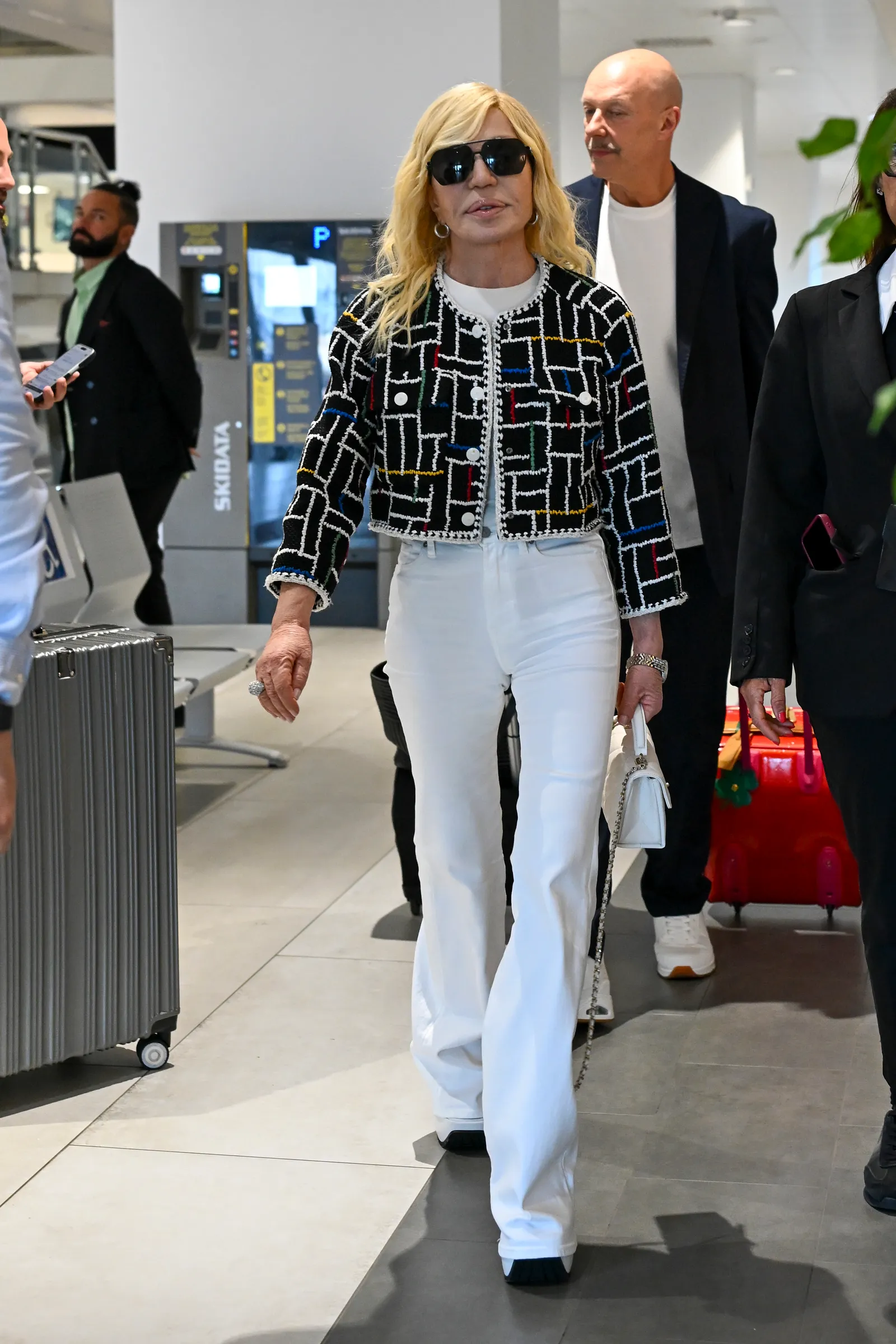 L'image peut contenir Donatella Versace Vêtements Pantalons Personne adulte Accessoires Sac Sac à main et appareils électroniques