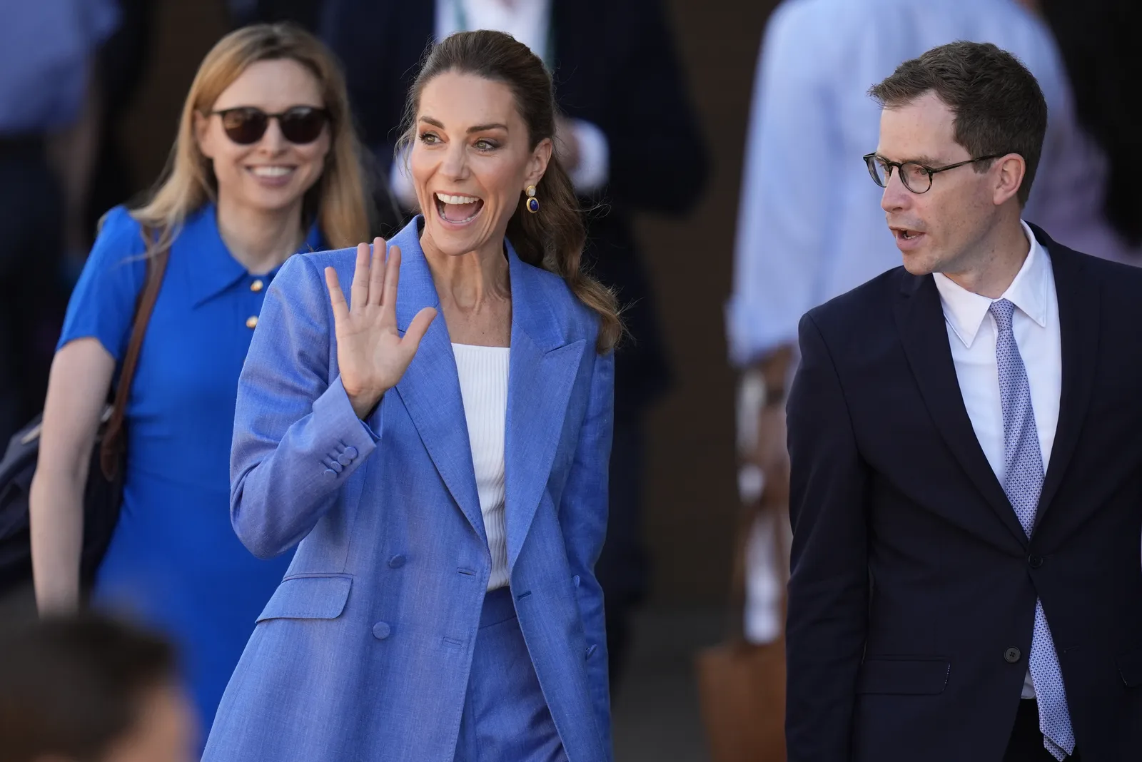 L'image peut contenir la tête d'une personne, un visage, des vêtements heureux, un manteau, une tenue de soirée, des accessoires de costume, des lunettes, un sourire et un adulte.