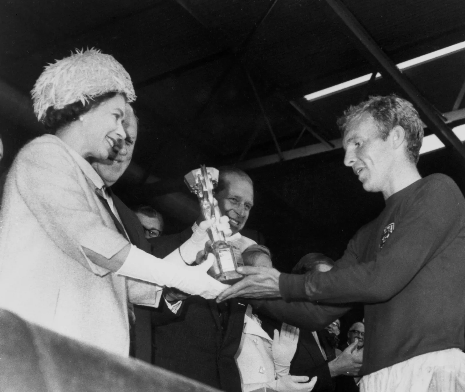 L'image peut contenir Elizabeth II Bobby Moore Philip Tomalin James Wade Bruce R. McConkie et un appareil électrique