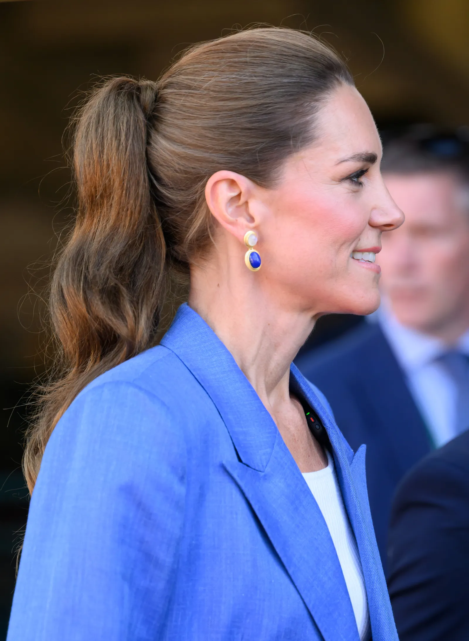 L'image peut contenir des cheveux d'une personne adulte, une queue de cheval, des vêtements de mariage, un manteau, une tenue formelle et un costume.