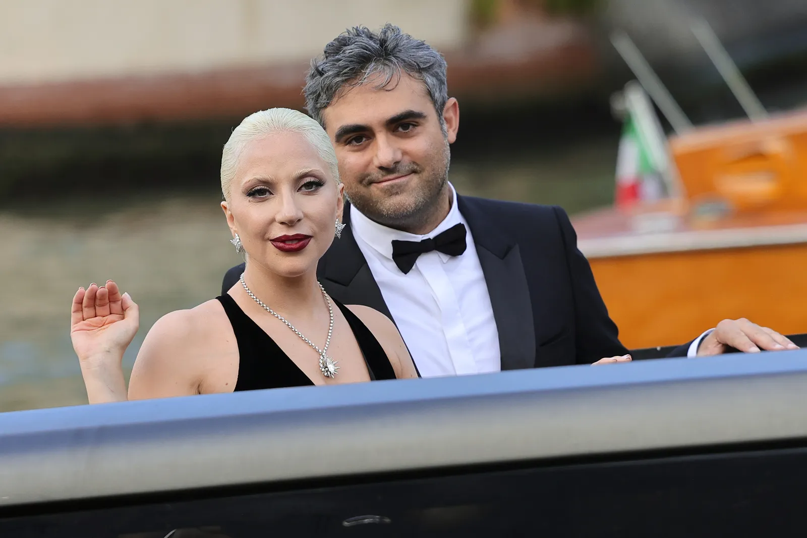 L'image peut contenir des vêtements de Lady Gaga, des vêtements de cérémonie, des accessoires de costume, une cravate, des bijoux, un collier, une personne et un photobombing.