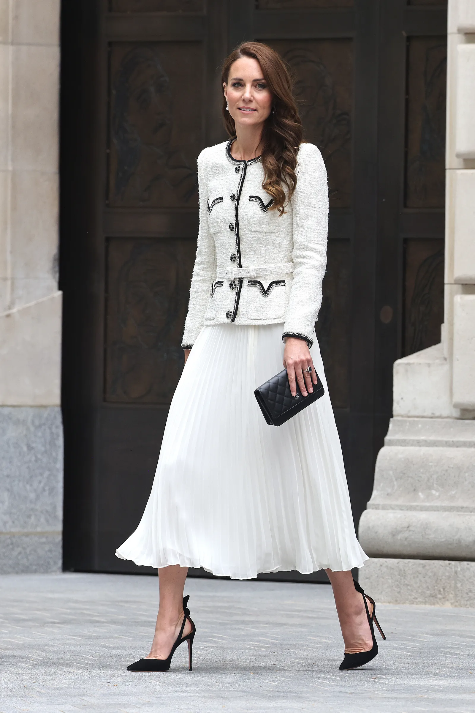 L'image peut contenir des vêtements à manches longues, jupe, manteau, personne adulte, pantalon, robe, vêtements de cérémonie, costume et chaussures.